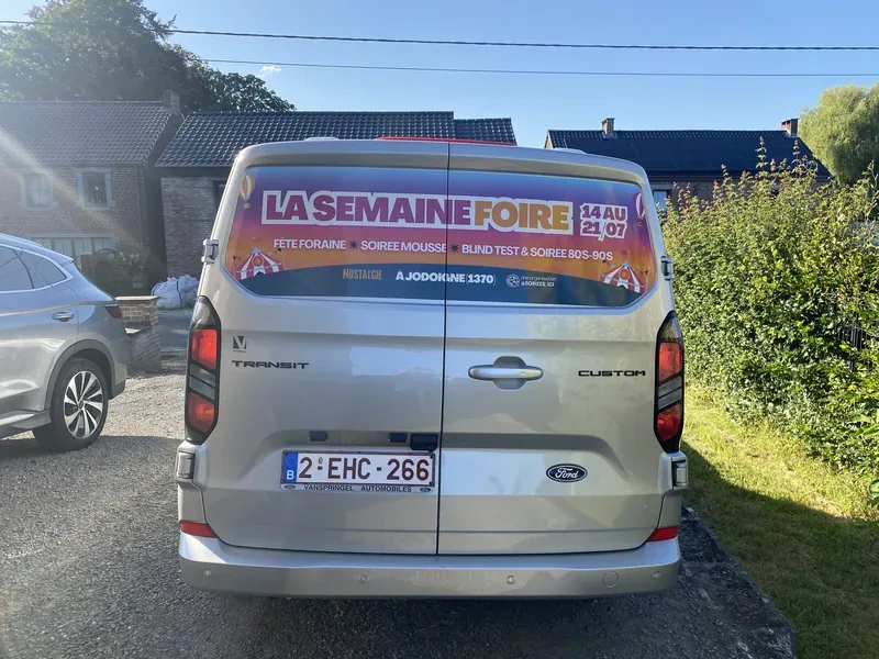 Affiche colorée collée sur la vitre arrière d'un Ford Transit Custom.