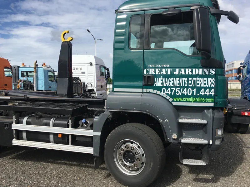 Nom d'entreprise et coordonnées floqués sur la cabine d'un camion benne.