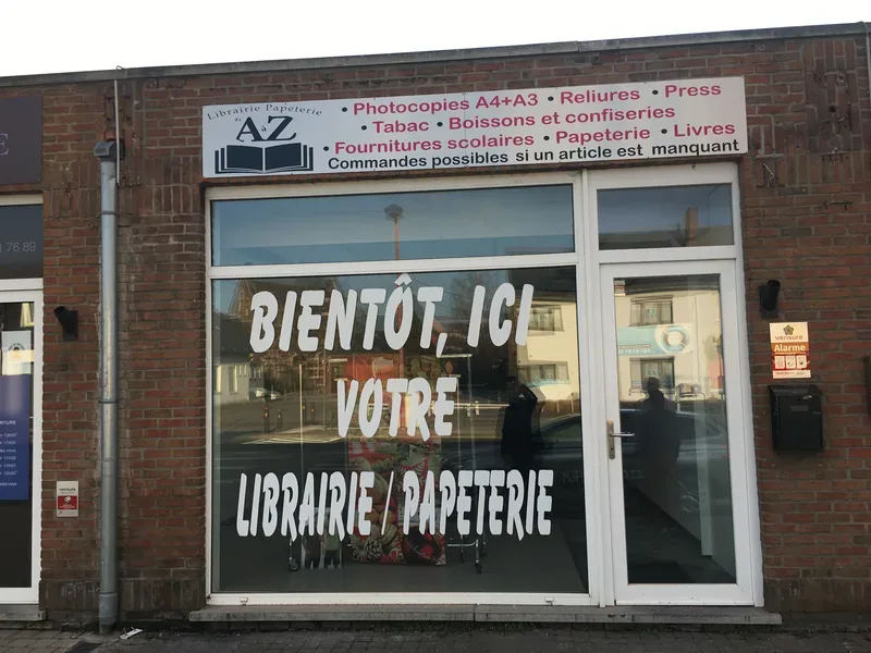 Grand lettrage blanc en vitrophanie annonçant l'ouverture prochaine d'une librairie papeterie.