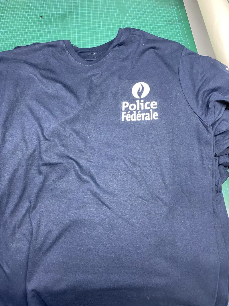 Gros plan sur un t-shirt marine floqué du logo Police Fédérale, tissu impeccable.