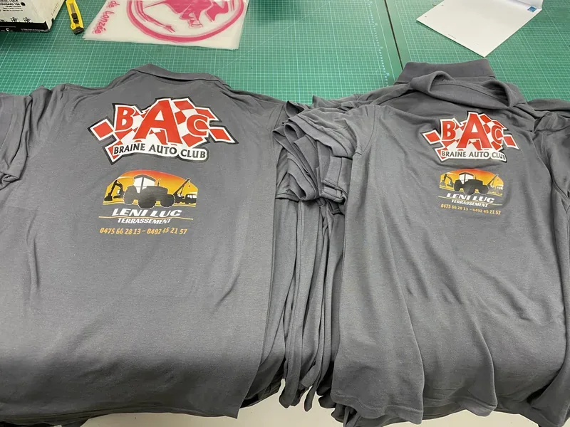 Pile de polos gris floqués d'un logo de club automobile.