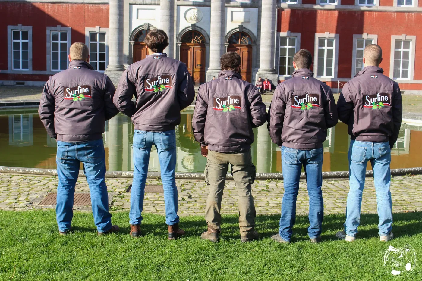 Équipe portant des vestes de travail personnalisées devant un bâtiment.