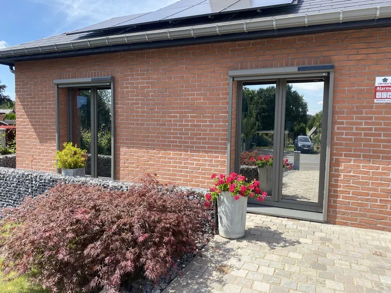 Baies vitrées teintées effet miroir sur une habitation moderne en briques.