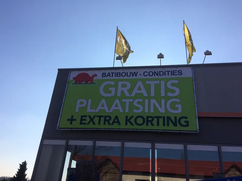 Bâche grand format vert et blanc tendue sur une façade.