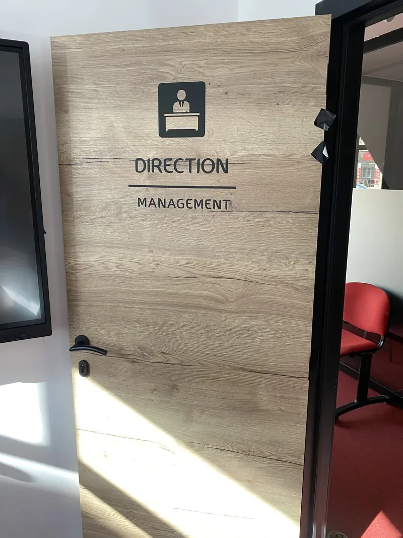 Habillage décoratif imitation bois avec pictogramme et lettrage Direction Management sur une porte de bureau.