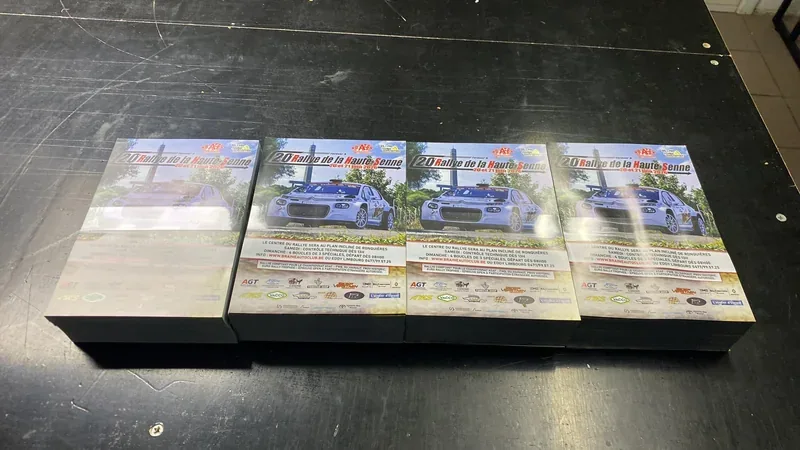 Programmes imprimés empilés pour un rallye automobile, illustrés d'une voiture de course.