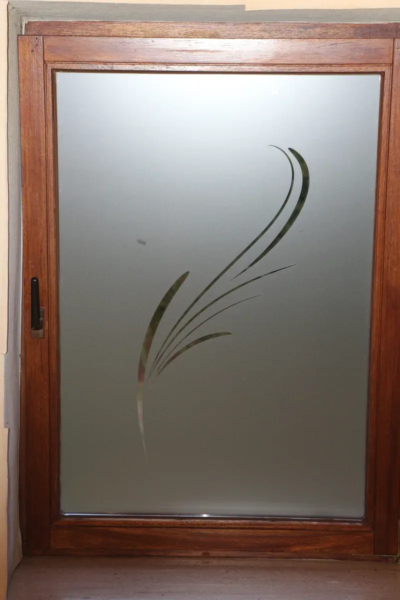 Porte vitrée dépolie ornée d'un motif de graminées.